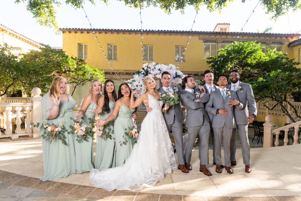 4 bridesmaids and 4 groomsmen surrounded a bride and groom smiling