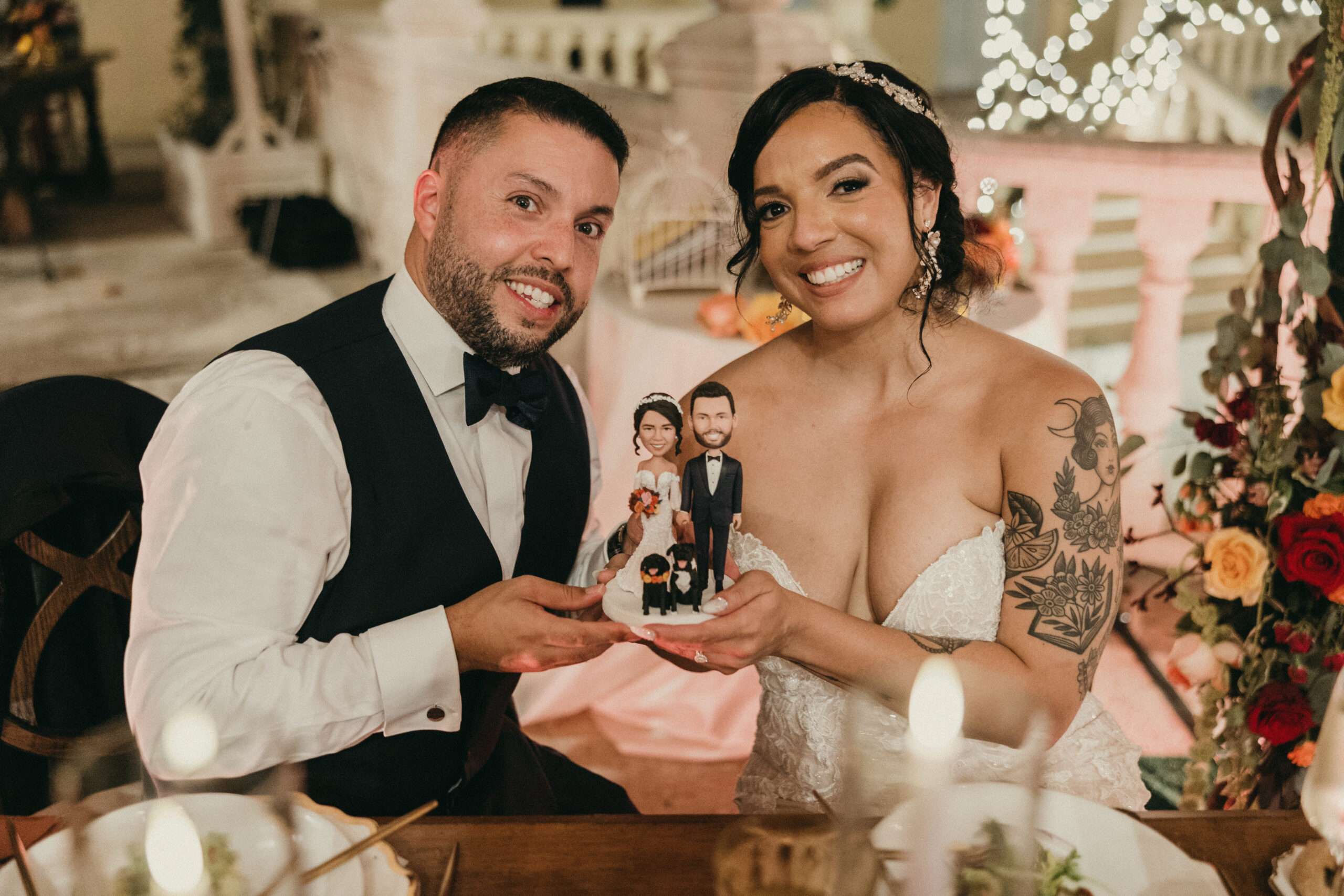 bride and groom holding cake topper of themselves and their two dogs